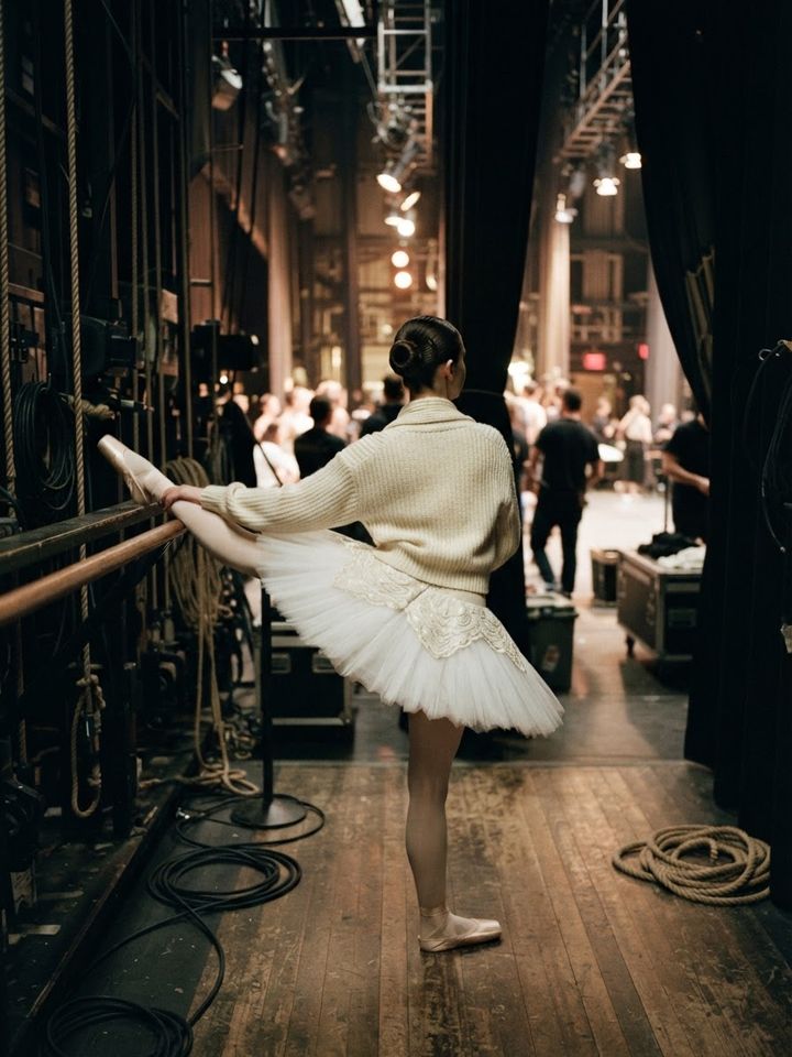 Dancer warming up in the wings in a tutu and cardigan